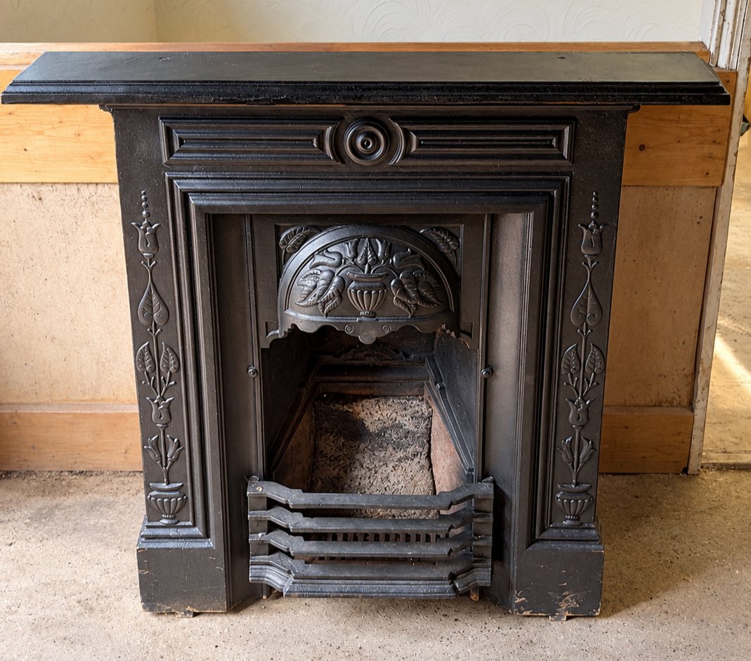 Cast iron fire surround with decorative tiled-style panels and grate